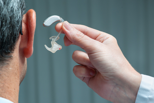 man receiving a hearing aid from his doctor after he experienced hearing loss from an auto accident