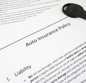overview of someone's auto insurance policy in Arizona. There is a black key sitting on top of the paperwork