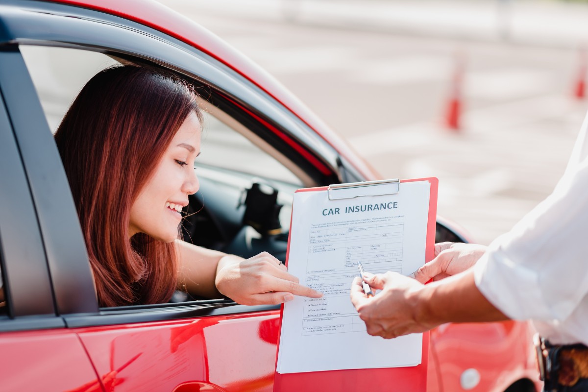 Man handing car insurance document to a woman in a car